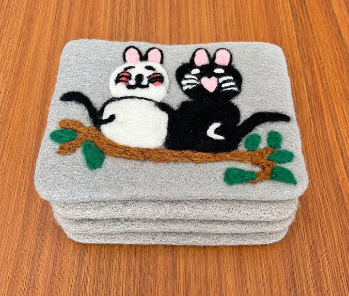 Stack of felt coasters embroidered with two cats on a branch