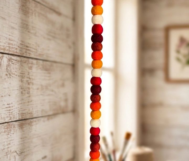 Colorful felt ball garland hanging by a window