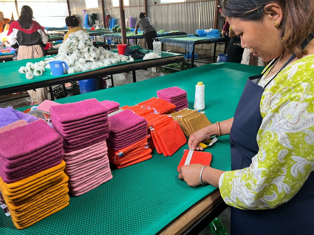 Woman artisan arranging stacks of colorful felt sheets in the workshop
