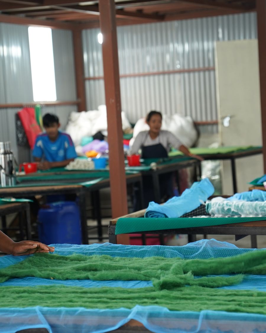 Women artisans at work across the long felting tables of the workshop