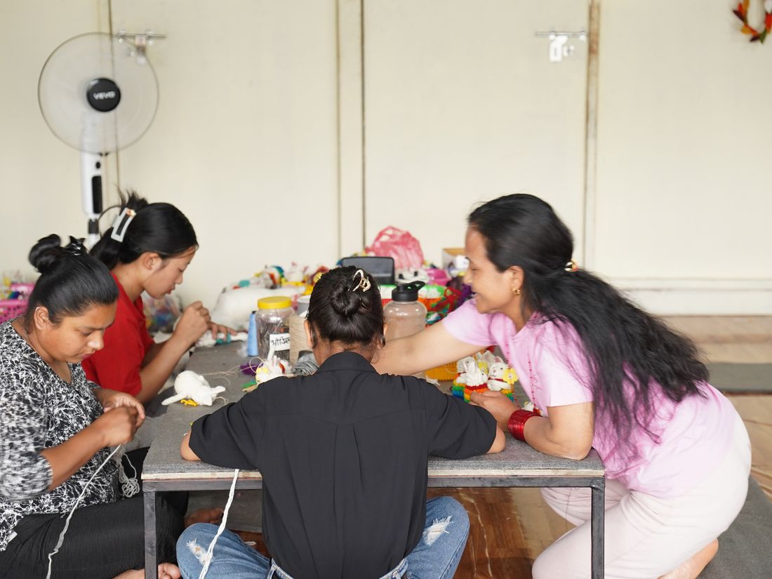 Women artisans sitting together around a table, crafting felt pieces